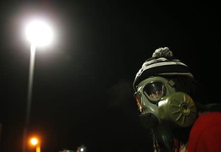 A protester wears a gas mask during a rally for Michael Brown outside the police department in Ferguson, Missouri, October 11, 2014. REUTERS/Jim Young
