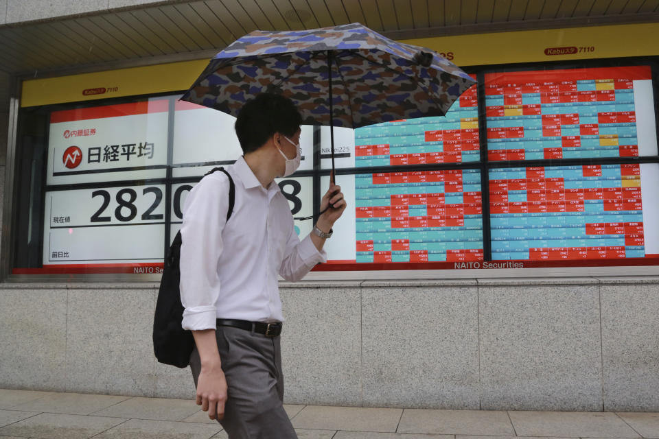 A man walks by an electronic stock board of a securities firm in Tokyo, Wednesday, Oct. 13, 2021. Shares were mixed in Asia on Wednesday after an up-and-down day on Wall Street ended with most benchmarks lower as traders waited for updates on inflation and corporate earnings. (AP Photo/Koji Sasahara)