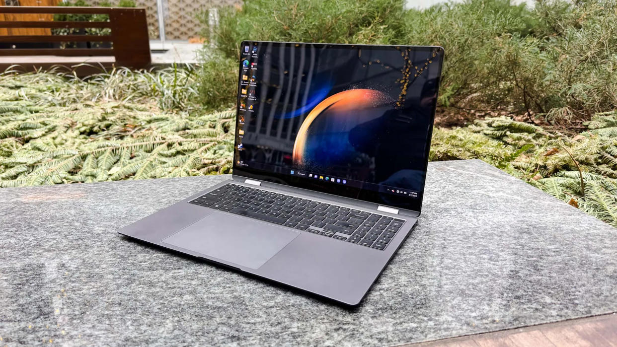  A laptop sitting on a backyard table with plants in the background. 