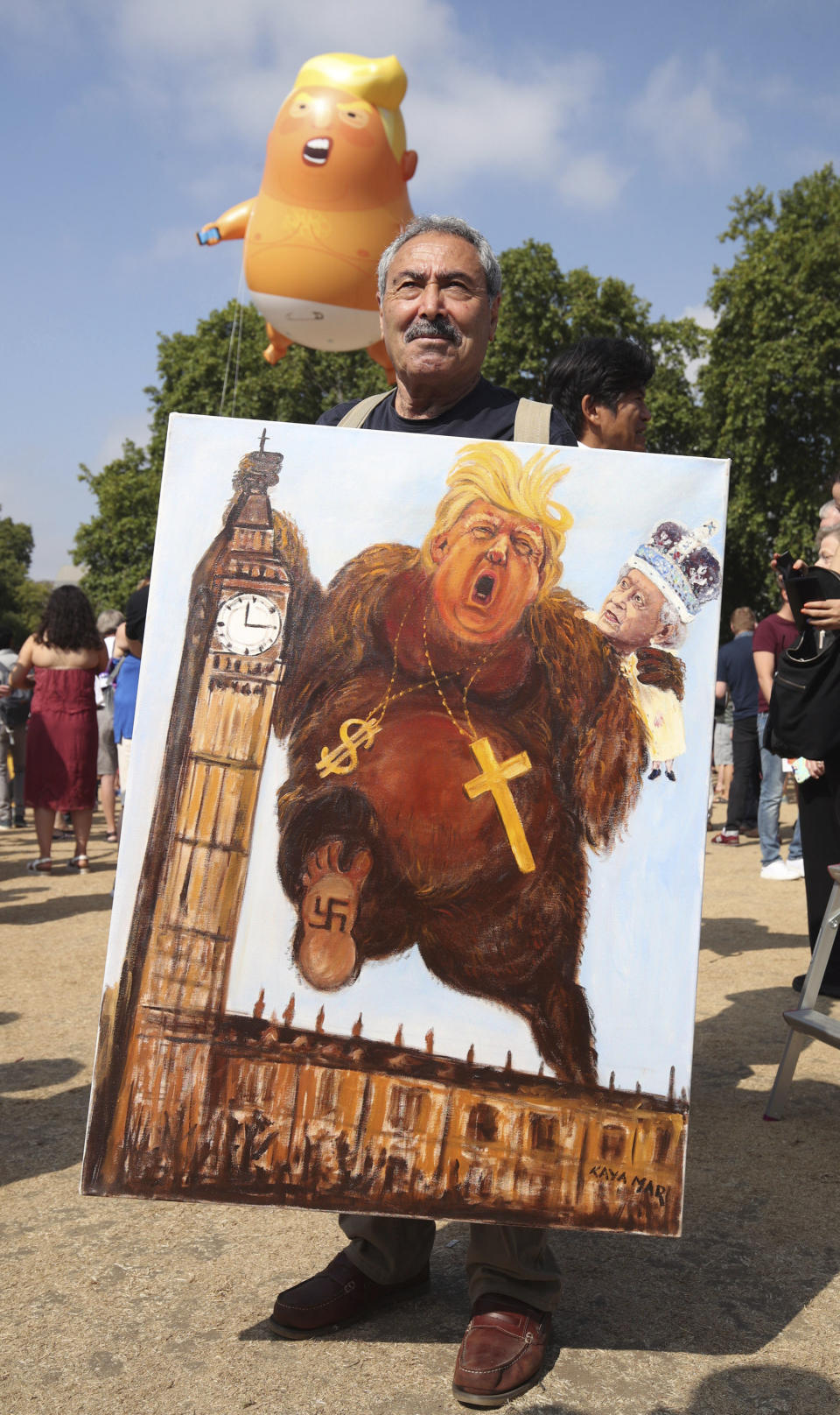 <p>Political artist Kaya Mar holds a painting depicting Donald Trump, during protests in London, July 13, 2018. Trump’s pomp-filled welcome to Britain was overshadowed Friday by an explosive interview in which he blasted Prime Minister Theresa May, blamed London’s mayor for terror attacks against the city and argued that Europe was “losing its culture” because of immigration. (Photo: Yui Mok/AP) </p>