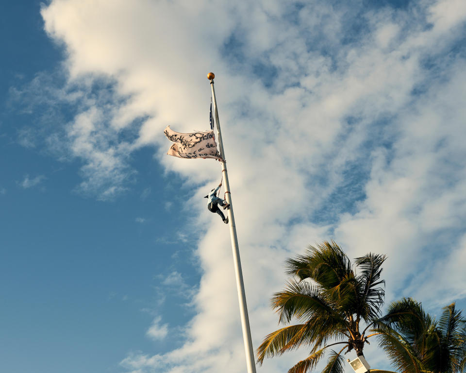 A protester scales a flag pole during a protest calling for Governor Ricardo Rosselló's resignation in the wake of 