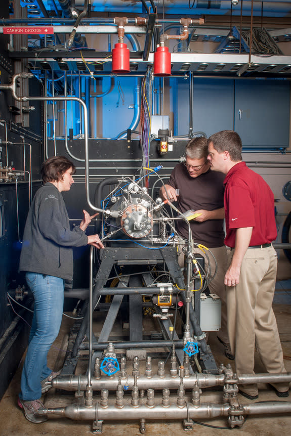 Task lead Tyler Hickman, in red shirt, and technicians inspect the 3D-printed rocket injector assembly as it’s installed in the Rocket Combustion Laboratory at NASA’s Glenn Research Center.