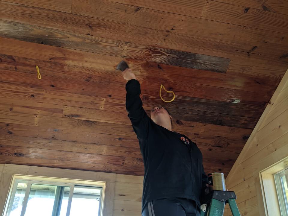 Katy Krebs standing on a ladder polishing the ceiling