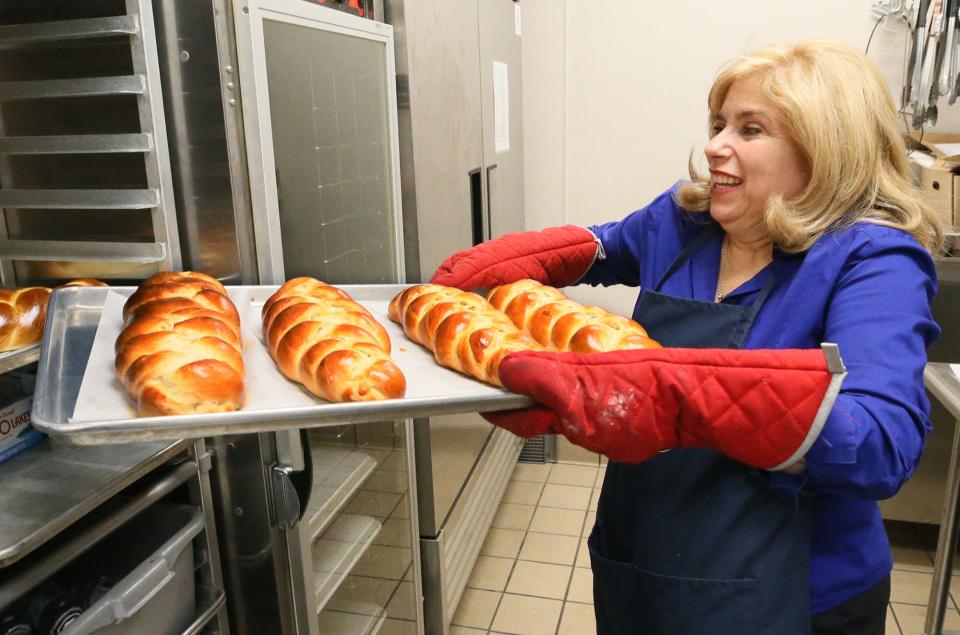 Kathryn Schlosser puts a tray of baked bread on a cooling rack as volunteer bakers from Annunciation's Philoptochos Society and Kalymnian Society of Campbell, Ohio, bake braided Greek Easter bread at Annunciation Greek Orthodox Church in Akron Tuesday.