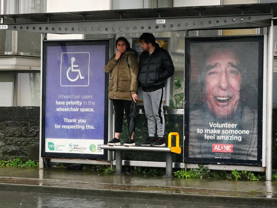 People stand on a bench at a bus stop in Dublin’s city centre (PA)