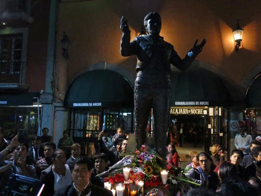 People gather around a statue depicting Mexican superstar songwriter and singer Juan Gabriel in Mexico City's Garibaldi plaza, Sunday Aug. 28, 2016. Juan Gabriel's publicist told The Associated Press that he died at 11:30 a.m. in his home in California. The singer, who was born Alberto Aguilera Valadez on Jan. 7, 1950, wrote his first song at age 13 and went on to compose more than 1,500 songs making him Mexico's leading singer-songwriter and top-selling artist with sales of more than 100 million albums. (AP Photo/Berenice Bautista)
