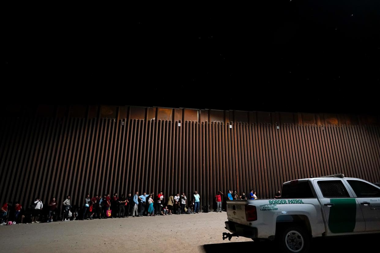 Migrants cross the border into Yuma on Aug. 23, 2022, despite a shipping container wall.