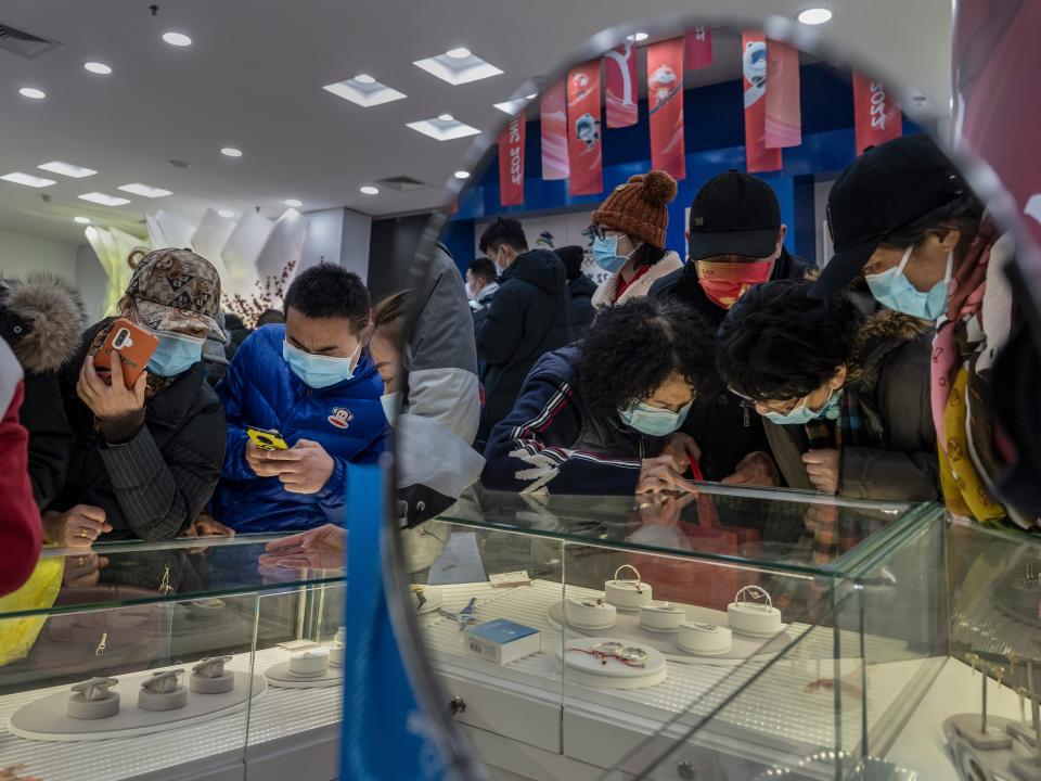 Customers crowd around a display case at the official Beijing 2022 Winter Olympics flagship souvenir store on February 8, 2022 in Beijing, China. Crowds of people have been lining up at authorized Beijing 2022 Winter Olympic stores trying to purchase Bing Dwen Dwen paraphernalia, the panda mascot of the Games. Items featuring the character have become a hot seller that Beijing 2022 merchandise stores cannot keep them in stock. Officials say the factories authorized to produce the souvenirs have been urged to increase production to help boost supplies. The sudden popularity of Bing Dwen Dwen, along with the Paralympic Games mascot Shuey Rhon Rhon, comes as most Chinese fans are unable to attend Olympics events in the host city because of China's zero-COVID protocols.