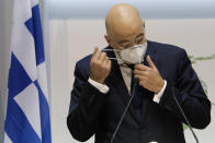 Greek Foreign Minister Nikos Dendias takes off his face mask during talk a press conference after a meeting with his Cyprus counterpart Nicos Christodoulides at the foreign ministry house in divided capital Nicosia, Cyprus, Dec. 4, 2020. Dendias and Christodoulides were meeting to coordinate their course of action ahead of a summit of European Union leaders next week to decide on a Turkish hydrocarbons search in waters where Cyprus and Greece claim exclusive rights and which EU officials have called " provocative"and "unlawful." (AP Photo/Petros Karadjias, Pool)