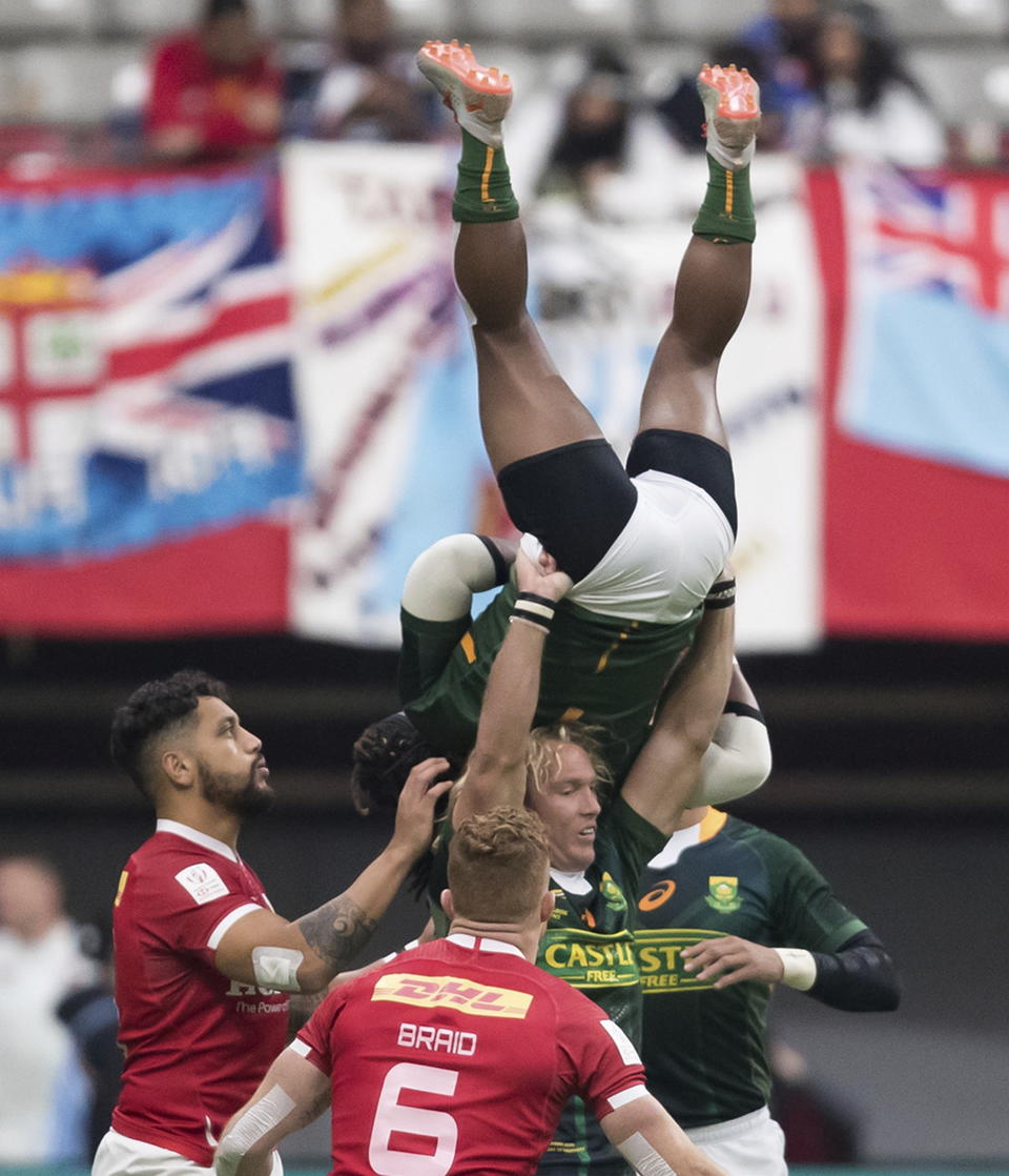 South Africa's Branco du Preez, top, is lifted by Werner Kok as he takes possession of the ball in front of Canada's Mike Fuailefau, left, and Connor Braid (6) during the bronze medal match at the Canada Sevens rugby tournament in Vancouver, British Columbia, Sunday, March 8, 2020. (Darryl Dyck/The Canadian Press via AP)