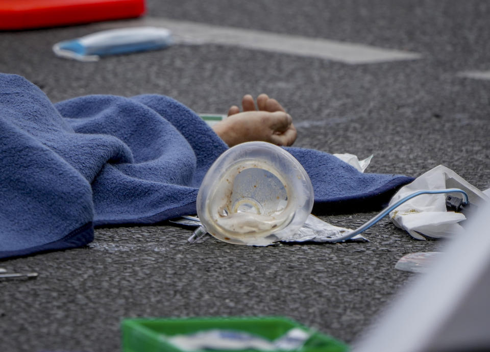 A covered body lies on the street after a car crashed into a crowd of people in central Berlin, Germany, Wednesday, June 8, 2022. (AP Photo/Michael Sohn)