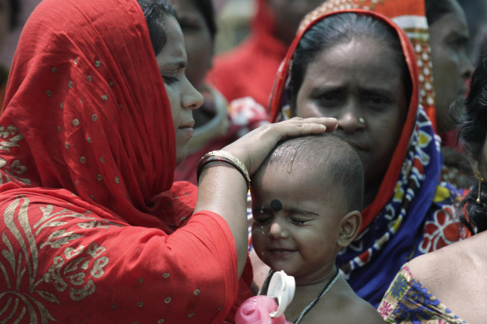 A woman wets the head of a child during an election rally addressed by Trinamool Congress leader and Chief Minister of West Bengal state Mamata Banerjee at Anchana in Mathurapur, about 60 kilometers south of Kolkata, India, Thursday, May 16, 2019. With 900 million of India's 1.3 billion people registered to vote, the Indian national election is the world's largest democratic exercise. The seventh and last phase of the elections will be held on Sunday. (AP Photo/Bikas Das)