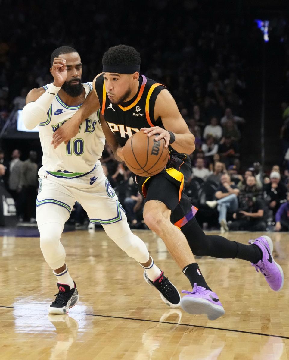 Phoenix Suns guard Devin Booker (1) drives past Minnesota Timberwolves guard Mike Conley (10) in the first half at Footprint Center in Phoenix on Nov. 15, 2023.