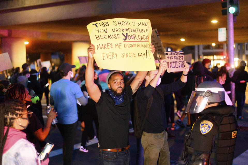 In this May 29, 2020, photo, demonstrators face off against police officers in Oakland, Calif. while protesting the Monday death of George Floyd, a handcuffed black man in police custody in Minneapolis. (AP Photo/Noah Berger)