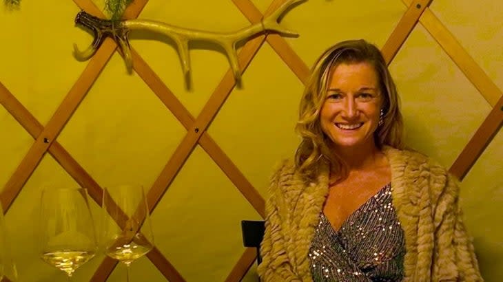 The author sitting in a yurt-like restaurant with an antler on a wall and wine glasses on the table