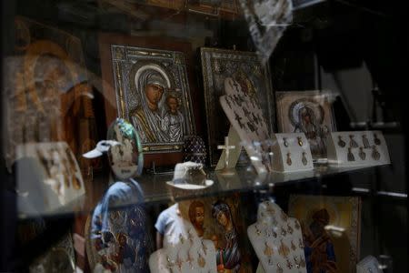 Tourists are reflected in the window of a shop selling Christian souvenirs in the Christian Quarter of Jerusalem's Old City June 21, 2016. REUTERS/Ronen Zvulun