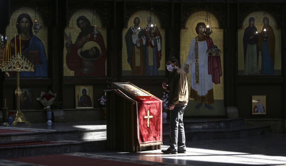 In this Thursday, April 16, 2020, photo, a man wearing a face mask to protect himself from the coronavirus prays at the altar of St. Clement Christian Orthodox church in Skopje, North Macedonia. For Orthodox Christians, this is normally a time of reflection, communal mourning and joyful release, of centuries-old ceremonies steeped in symbolism and tradition. But this year, Easter - by far the most significant religious holiday for the world's roughly 300 million Orthodox - has essentially been cancelled. (AP Photo/Boris Grdanoski)