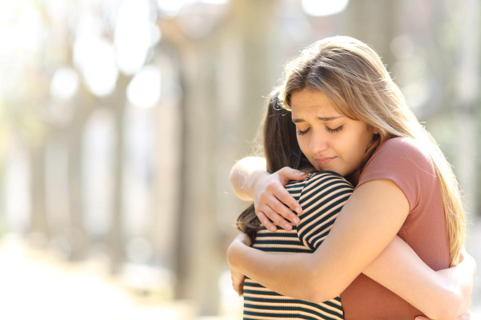 A girl offers a comforting hug to her friend