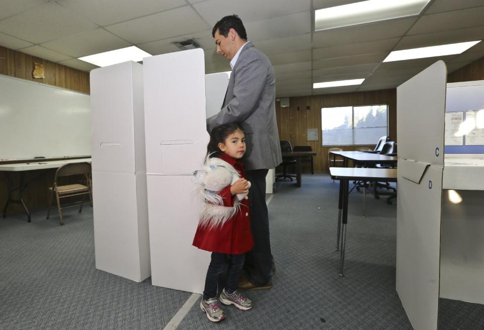 San Diego mayoral candidate David Alvarez cast his ballot as a his daughter, Izel, holds onto his leg at a polling location in the Logan Heights neighborhood where Alvarez grew up and still lives Tuesday, Feb. 11, 2014 in San Diego. (AP Photo/Lenny Ignelzi)