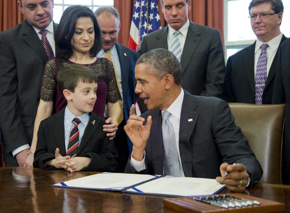 President Barack Obama talks to Jake Miller, left, accompanied by Ellyn Miller, behind Jake, brother and mother of Gabriela Miller, before signing into law the H.R. 2019, the Gabriella Miller Kids First Research Act, in the Oval Office of the White House in Washington, Thursday, April 3, 2014. (AP Photo/Manuel Balce Ceneta)