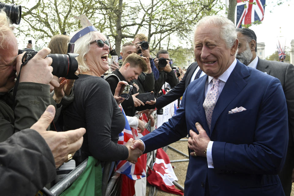 FILE - Britain's King Charles III greets well-wishers outside Buckingham Palace, in London, Friday, May 5, 2023 a day before his coronation takes place at Westminster Abbey. A year after the death of Queen Elizabeth II triggered questions about the future of the British monarchy, King Charles III’s reign has been marked more by continuity than transformation, by changes in style rather than substance. (Toby Melville, Pool via AP, File)