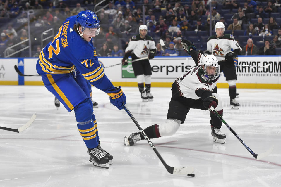 Buffalo Sabres center Tage Thompson, left, shoots while defended by Arizona Coyotes defenseman Juuso Valimaki, front right, during the second period of an NHL hockey game in Buffalo, N.Y., Monday, Dec. 11, 2023. (AP Photo/Adrian Kraus)