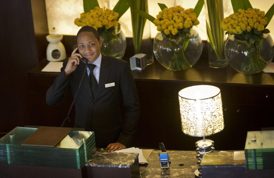 In this photo taken Wednesday, Sept. 26, 2012, a receptionist takes a call at the front desk of the Sankara Nairobi hotel in Nairobi, Kenya. International hotel developers are planning nearly 40,000 new rooms across Africa in the coming years, the continent's business travel is increasing, and Africa's middle class will soon begin leisure travel en masse. (AP Photo/Ben Curtis)