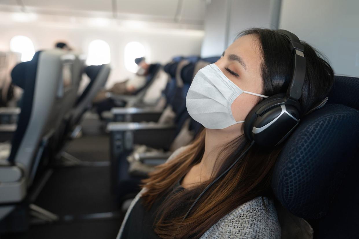 Portrait of a Latin American woman traveling by plane wearing a facemask and sleeping onboard