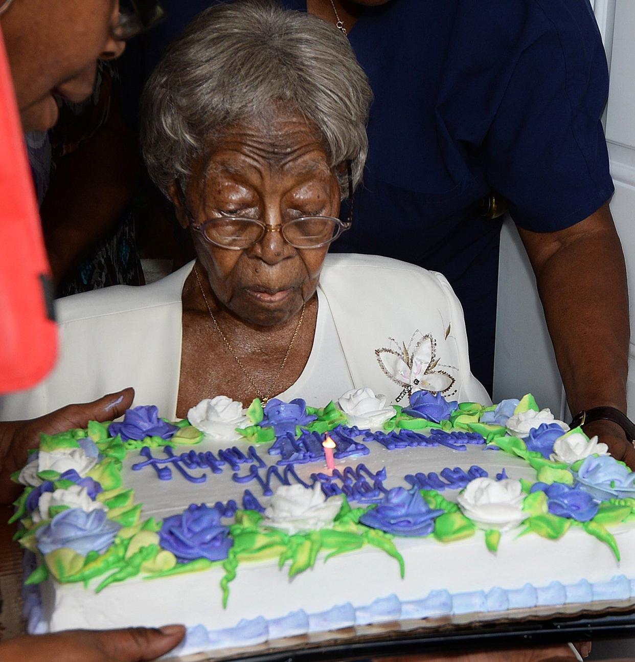 FILE - Family members hold the birthday cake as Hester "Granny" Ford blows out the candle at Ford's 111th birthday party at her home. 