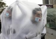 College students wearing masks cover themselves with plastic bags as they participate in a performance art to raise awareness of air pollution, in Xi'an, Shaanxi province December 5, 2013. China's stability-obsessed leadership has become increasingly concerned by the abysmal air quality in cities, as it plays into popular resentment over political privilege and rising inequality in the world's second-largest economy. REUTERS/Stringer (CHINA - Tags: ENVIRONMENT SOCIETY) CHINA OUT. NO COMMERCIAL OR EDITORIAL SALES IN CHINA