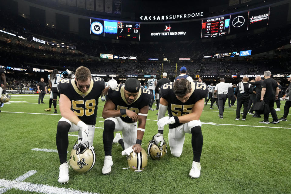 New Orleans Saints linebacker Ty Summers, from left, linebacker Andrew Dowell and linebacker Kaden Elliss say a prayer on the field for Buffalo Bills player Damar Hamlin after an NFL football game between the Carolina Panthers and the New Orleans Saints in New Orleans, Sunday, Jan. 8, 2023. (AP Photo/Gerald Herbert)