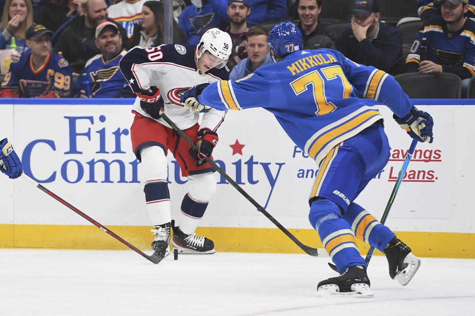 Columbus Blue Jackets' Eric Robinson (50) fights for the puck against St. Louis Blues' Niko Mikkola (77) during the first period of an NHL hockey game Saturday, Nov. 27, 2021, in St. Louis. (AP Photo/Michael Thomas)