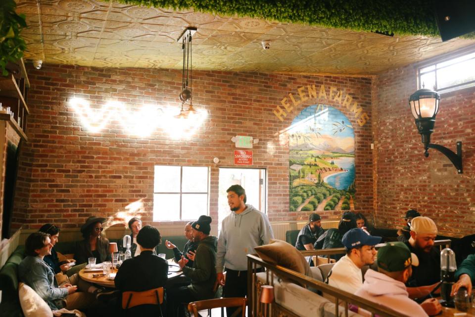 People sitting in a brick-walled space under cannabis-brand art.