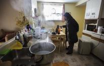 REFILE - CLARIFYING SECOND SENTENCE Hazel Crawley tends to her cat behind a pot of boiling hot water, used to raise the humidity in her home that has no heat or power following an ice storm in Toronto, December 27, 2013. Over 30,000 homes and businesses are still without power in North America's fourth largest city, according to the utility company Toronto Hydro. REUTERS/Mark Blinch (CANADA - Tags: ENVIRONMENT ANIMALS)