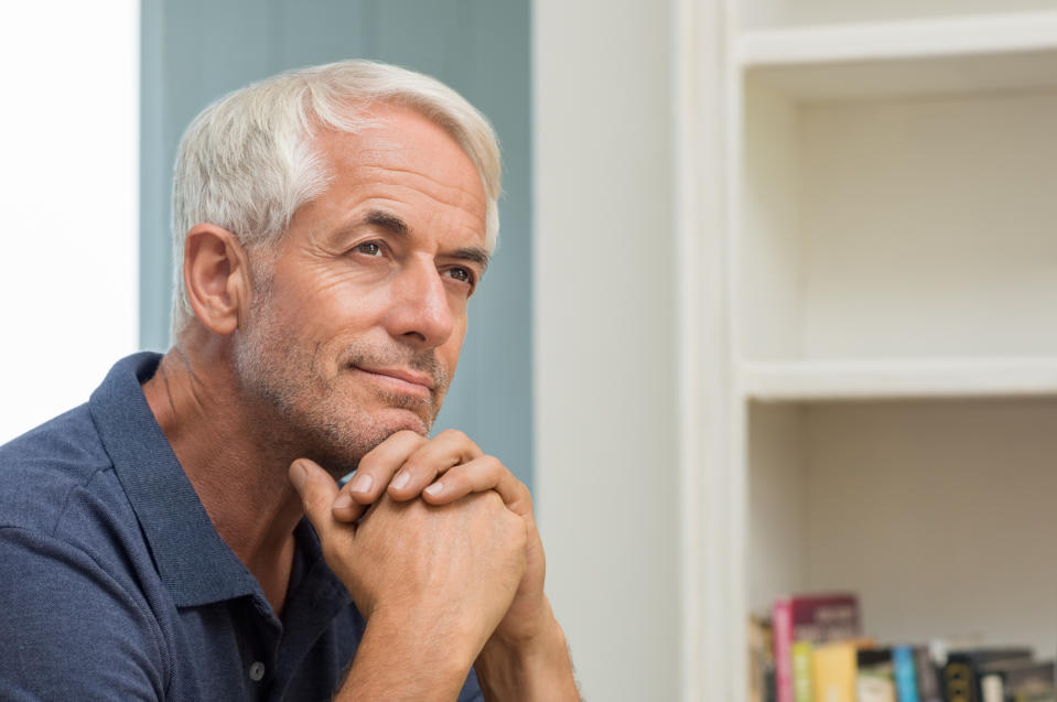 Older man resting head on hands with thoughtful expression
