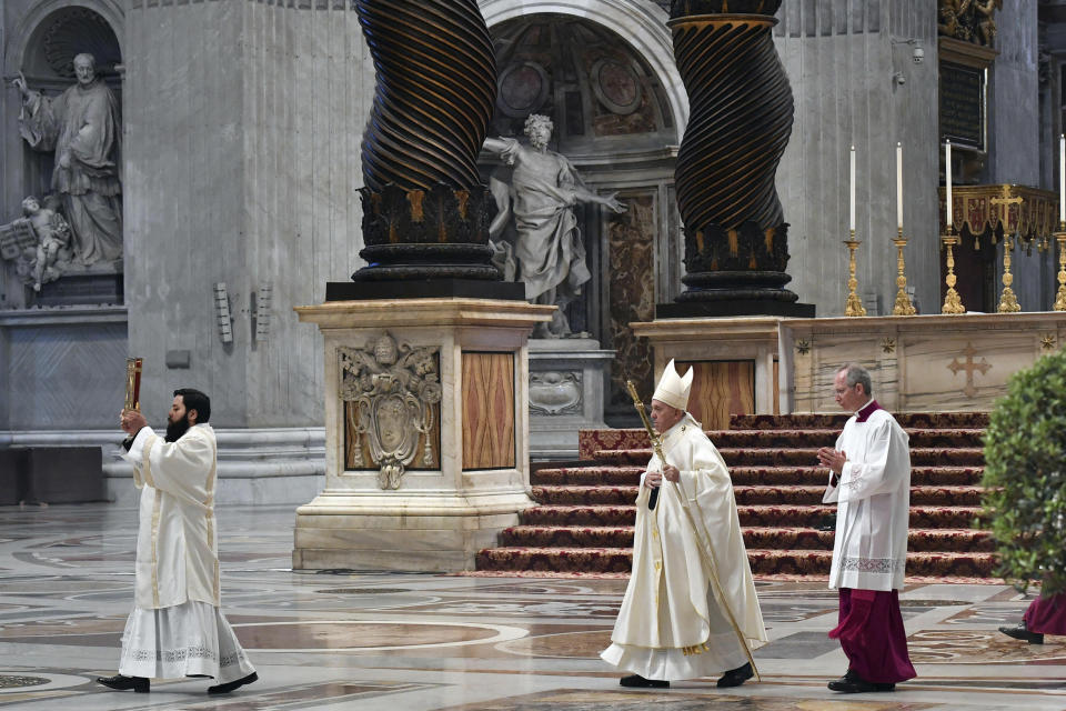 Pope Francis, center, arrives to attend a Mass for Holy Thursday, inside St. Peter's Basilica at the Vatican, Thursday, April 9, 2020. Francis celebrated the Holy Week Mass in St. Peter's Basilica, which was largely empty of faithful because of restrictions aimed at containing the spread of COVID-19. The new coronavirus causes mild or moderate symptoms for most people, but for some, especially older adults and people with existing health problems, it can cause more severe illness or death. (Alessandro Di Meo/Pool Photo via AP)
