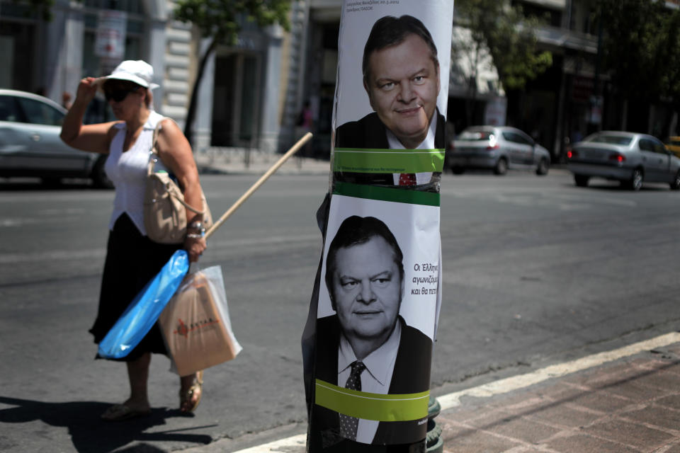 A woman holding shopping bags waits for a bus next to electoral posters of Greek socialist party leader Evangelos Venizelos that read "We Greeks are fighting and we will succeed," in central Athens, Tuesday, June, 12, 2012. Greece holds crucial national elections on Sunday, June 17, that could ultimately determine whether the deeply-indebted, recession bound country remains within the eurozone. The elections on May 6 resulted in a hung parliament. (AP Photo/Petros Giannakouris)