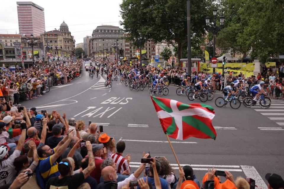 A spectator waves a Basque regional flag as the pack of riders cycles at the start of the 1st stage of the 110th edition of the Tour de France cycling race 182 km departing and finishing in Bilbao in northern Spain on July 1 2023 Photo by Thomas SAMSON  AFP Photo by THOMAS SAMSONAFP via Getty Images
