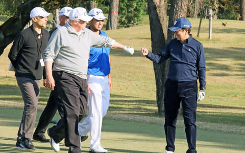  U.S. President Donald Trump gestures to Japan's Prime Minister Shinzo Abe as they play golf at the Kasumigaseki Country Club  - Credit: KYODO/Reuters