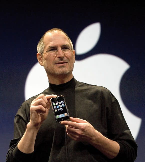 Apple's former CEO Steve Jobs holding the original iPhone.