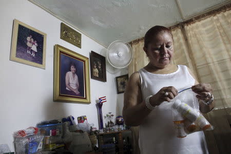 Obdulia Lopez, a 60-year-old retired social services worker, talks to Reuters while taking her medication at her home in Juana Diaz, Puerto Rico, March 18, 2016. REUTERS/Alvin Baez