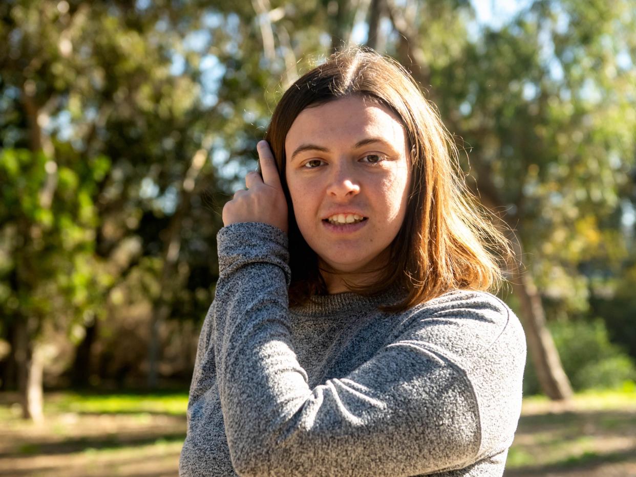 Madison Holman, a non-speaking autistic woman, in a gray sweater