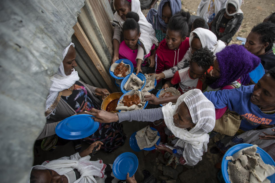 Displaced Tigrayans line up to receive food donated by local residents at a reception center for the internally displaced in Mekele, in the Tigray region of northern Ethiopia, on Sunday, May 9, 2021. In war-torn Tigray, more than 350,000 people already face famine, according to the U.N. and other humanitarian groups. It is not just that people are starving; it is that many are being starved, The Associated Press found. (AP Photo/Ben Curtis)