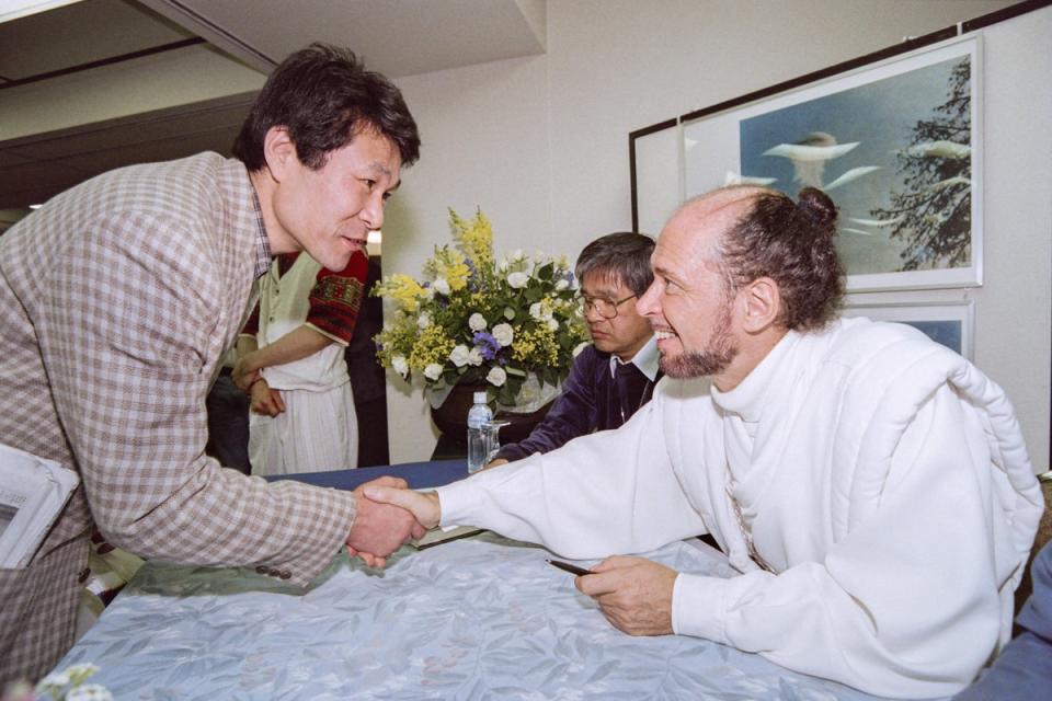 Claude Vorilhon shakes hands with someone during a seminar in Tokyo on 20 April 1997 (JUNJI KUROKAWA/AFP via Getty Images))