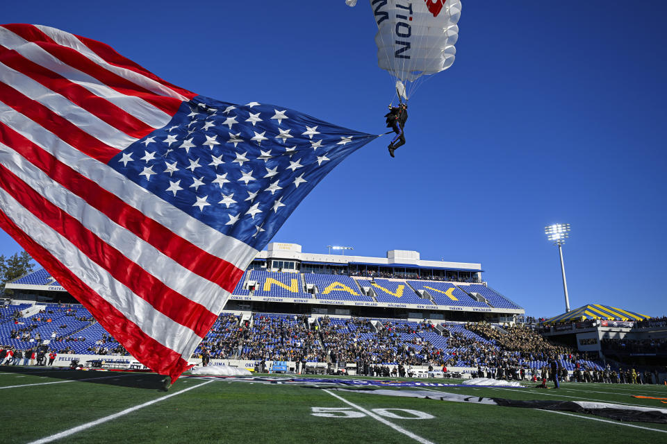 A member of Team Fastrax Parachute Jump Team lands on the field with an American flag before the Military Bowl NCAA college football game between Duke and UCF, Wednesday, Dec. 28, 2022, in Annapolis, Md. (AP Photo/Terrance Williams)