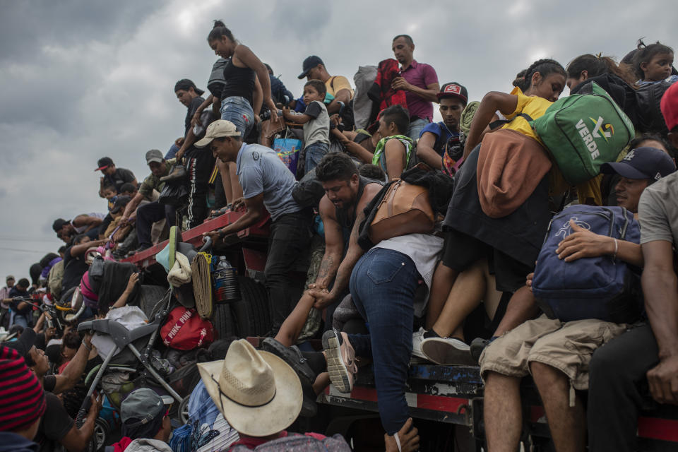 Migrants help fellow migrants onto the bed of a trailer in Jesus Carranza, in the Mexican state of Veracruz, Wednesday, Nov. 17, 2021. A group of mainly Central American migrants are attempting to reach the U.S.-Mexico border. (AP Photo/Felix Marquez)