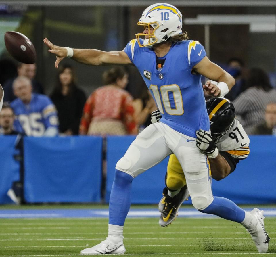 Chargers quarterback Justin Herbert flips a pass to Joshua Palmer while tackled by Steelers defensive end Cameron Heyward.