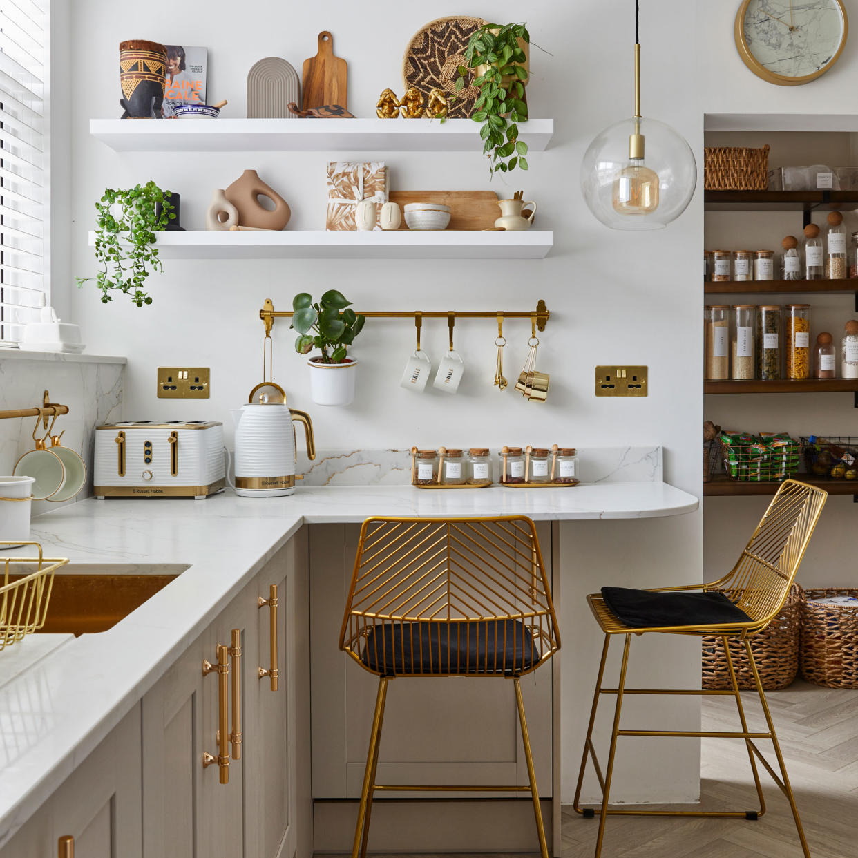  Kitchen with pale units, white work surface and gold metallic accessories. 