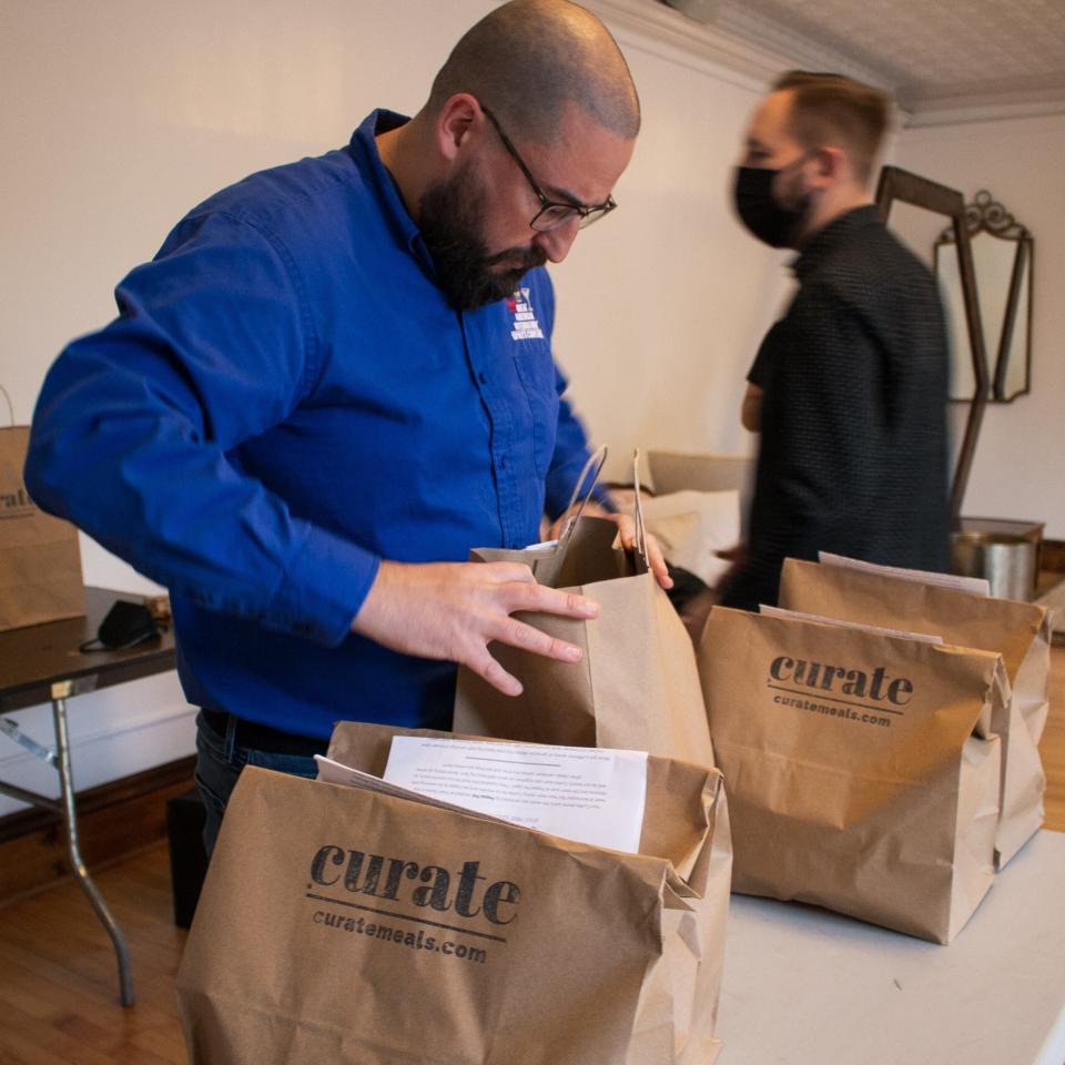 Chris Lindstrom, left, packs a meal for CurAte, which offers deliveries of mystery meals.