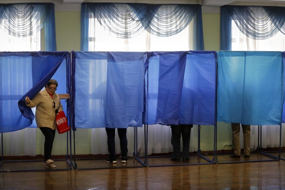 A woman leaves a booth at a polling station, during the second round of presidential elections in Kiev, Ukraine, Sunday, April 21, 2019. Top issues in the election have been corruption, the economy and how to end the conflict with Russia-backed rebels in eastern Ukraine. (AP Photo/Sergei Grits)